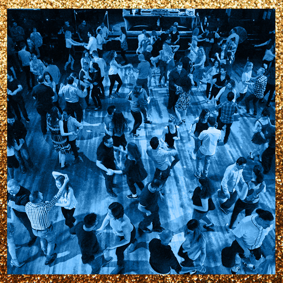 A large group of people are partner dancing while a band plays live music